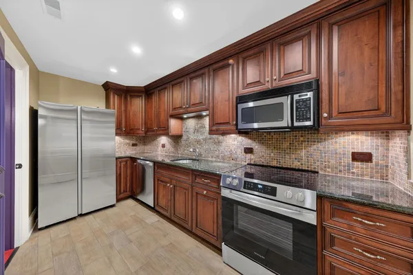 a kitchen with granite countertop wooden cabinets stainless steel appliances and a window