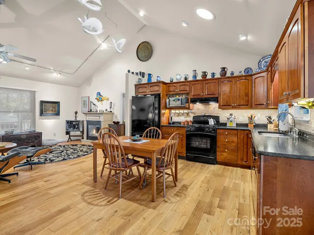 a kitchen with stainless steel appliances granite countertop a stove top oven a sink a dining table and chairs with wooden floor