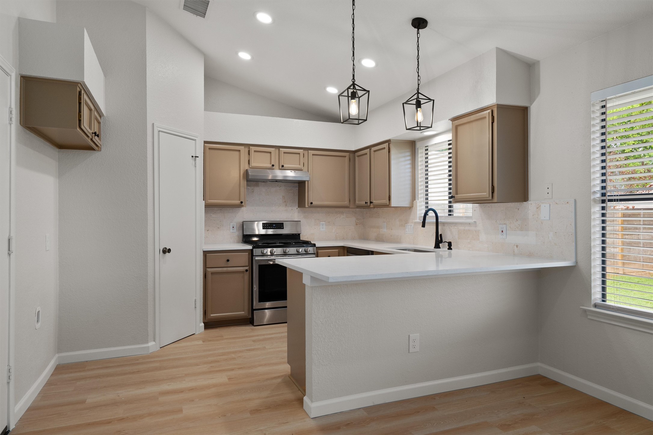 1401 Plum Creek Road Cedar Park, TX 78613 - Photo 10 of 30 Kitchen featuring tasteful backsplash, stainless steel range with gas stovetop, a peninsula, light wood finished floors, and lofted ceiling