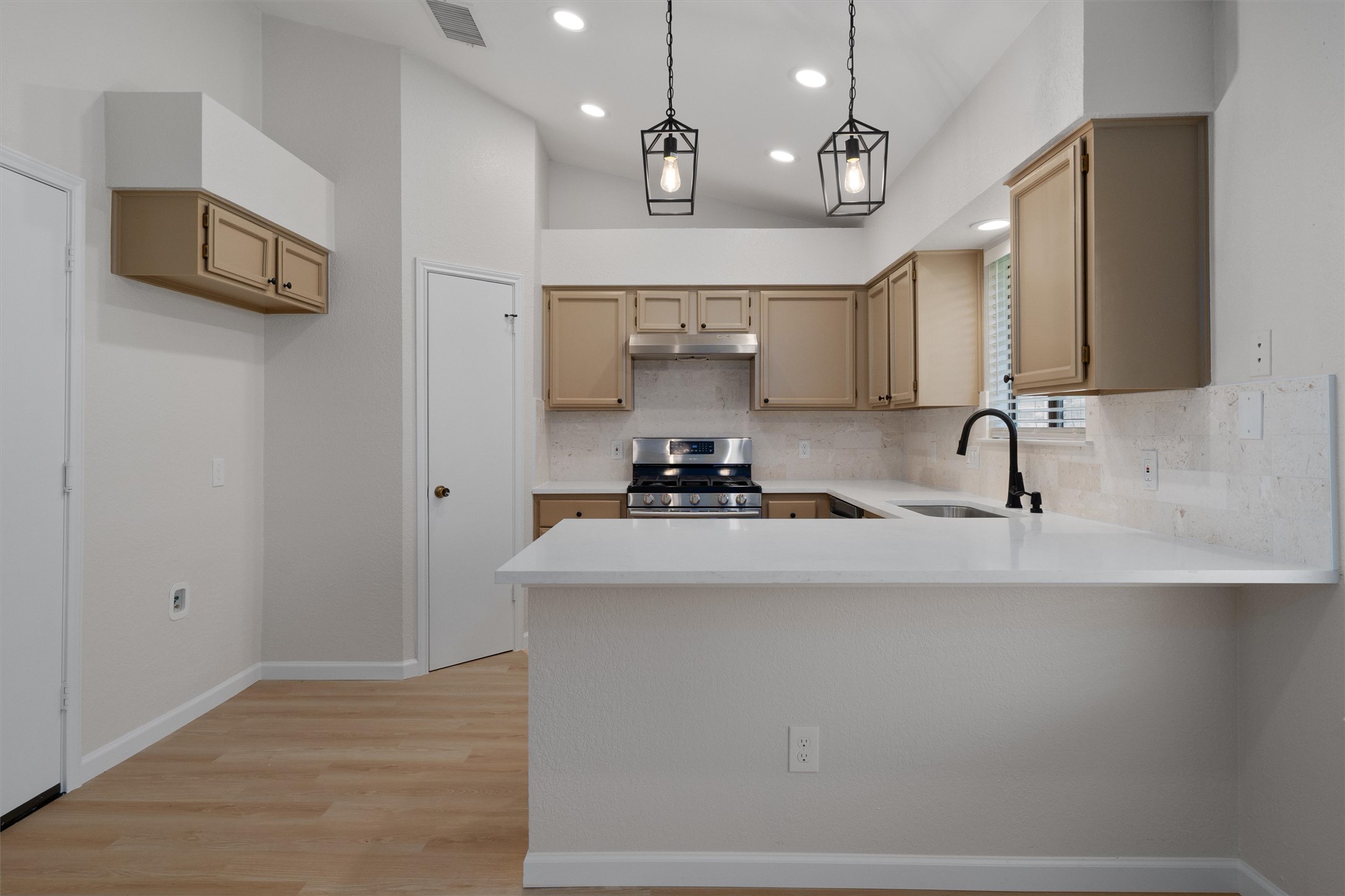 1401 Plum Creek Road Cedar Park, TX 78613 - Photo 11 of 30 Kitchen with a peninsula, backsplash, stainless steel range with gas cooktop, light wood-style flooring, and hanging light fixtures