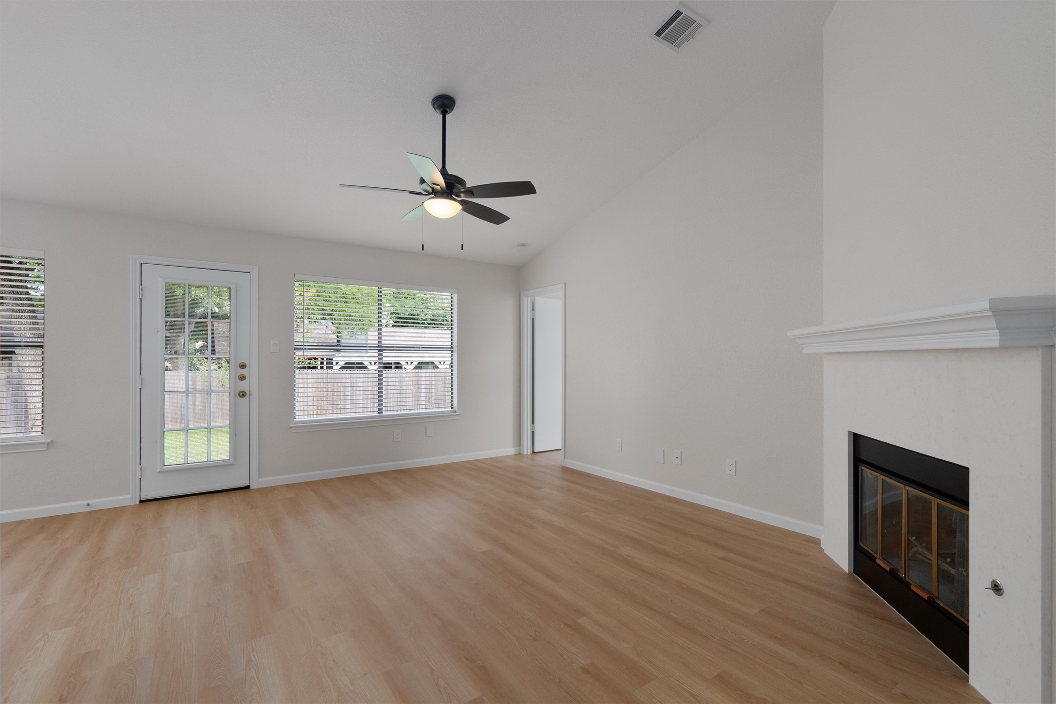 1401 Plum Creek Road Cedar Park, TX 78613 - Photo 7 of 30 Unfurnished living room featuring vaulted ceiling, ceiling fan, light wood-type flooring, and a glass covered fireplace
