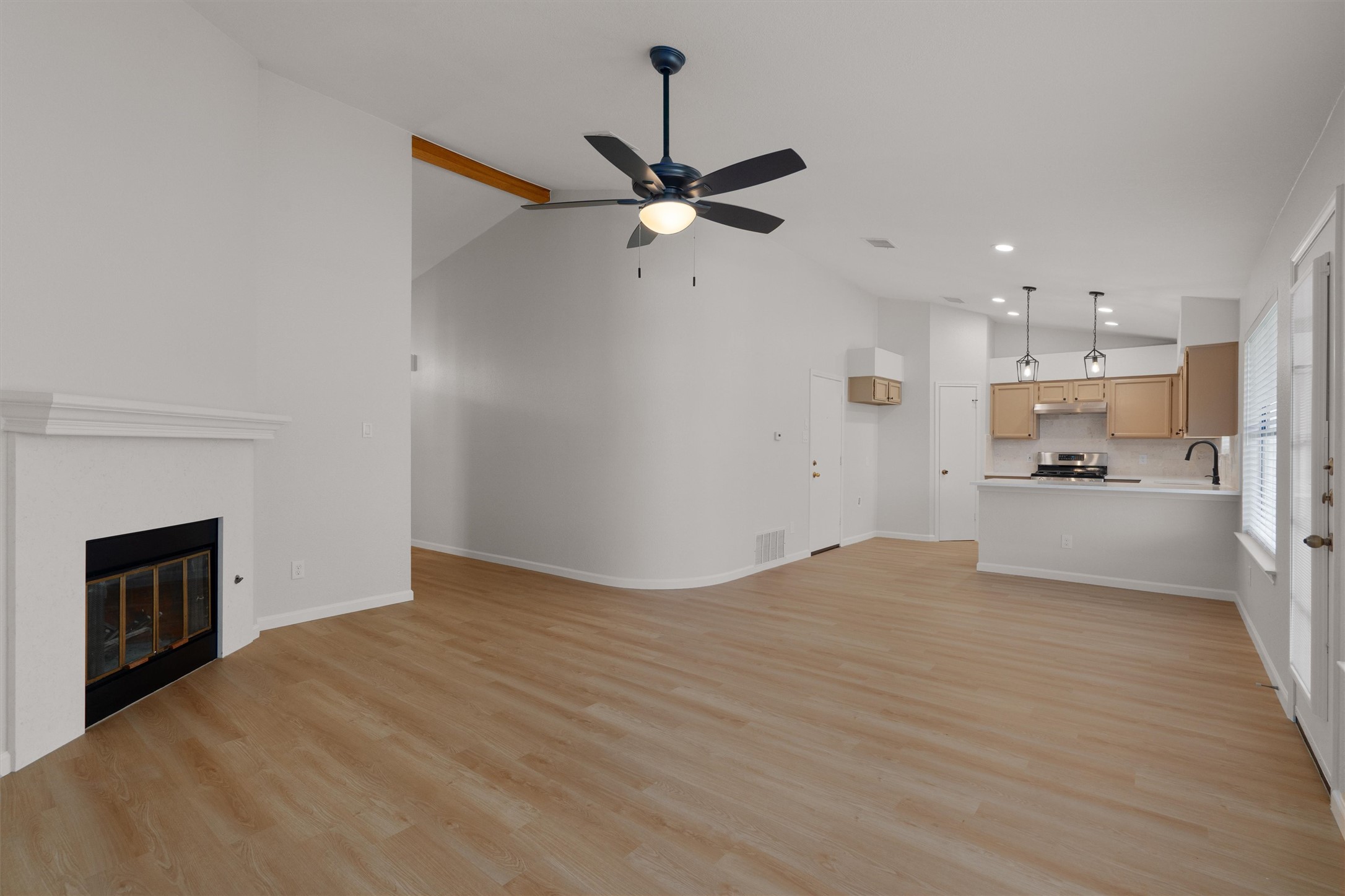 1401 Plum Creek Road Cedar Park, TX 78613 - Photo 8 of 30 Unfurnished living room with vaulted ceiling, a ceiling fan, light wood-style floors, and a glass covered fireplace