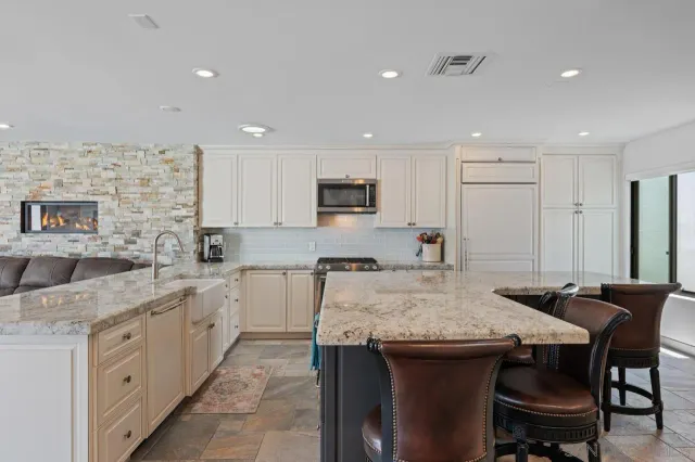a view of kitchen that has a lot of counter top space and appliances