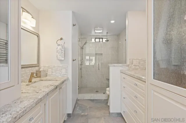 a bathroom with a granite countertop double vanity sink and mirror