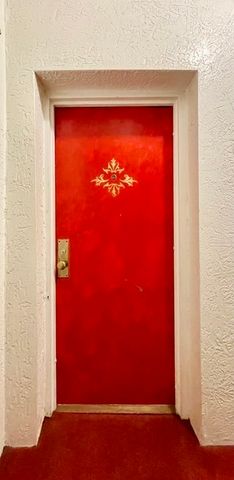 a view of an empty room with chandelier fan and window