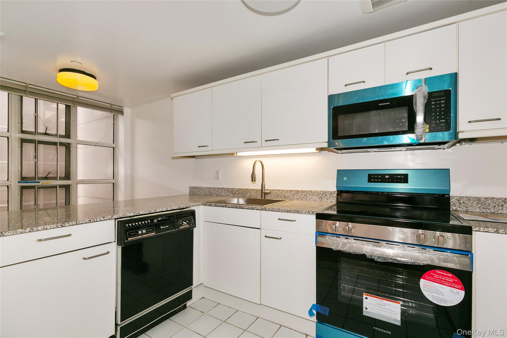 100 Cutter Mill Road, Unit 2C Great Neck, NY 11021 - Photo 15 of 29 a kitchen with stainless steel appliances granite countertop a stove a sink and a microwave