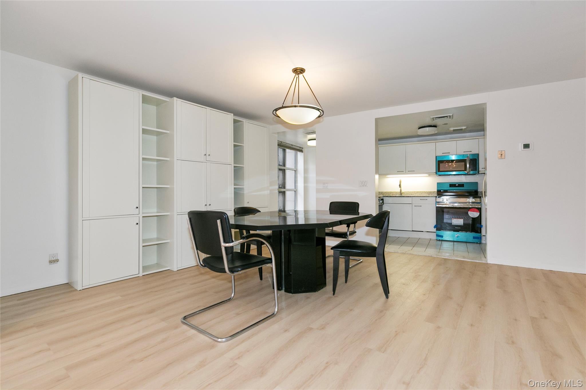 100 Cutter Mill Road, Unit 2C Great Neck, NY 11021 - Photo 9 of 29 a dining room with wooden floor a chandelier a wooden table and chairs