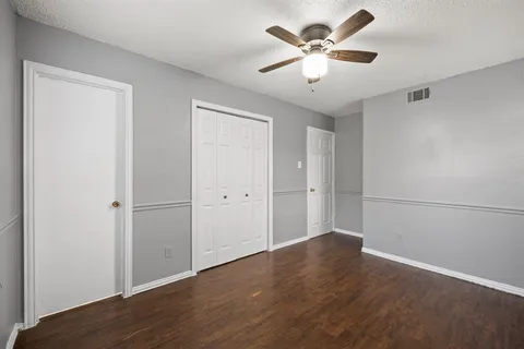 an empty room with wooden floor and ceiling fan