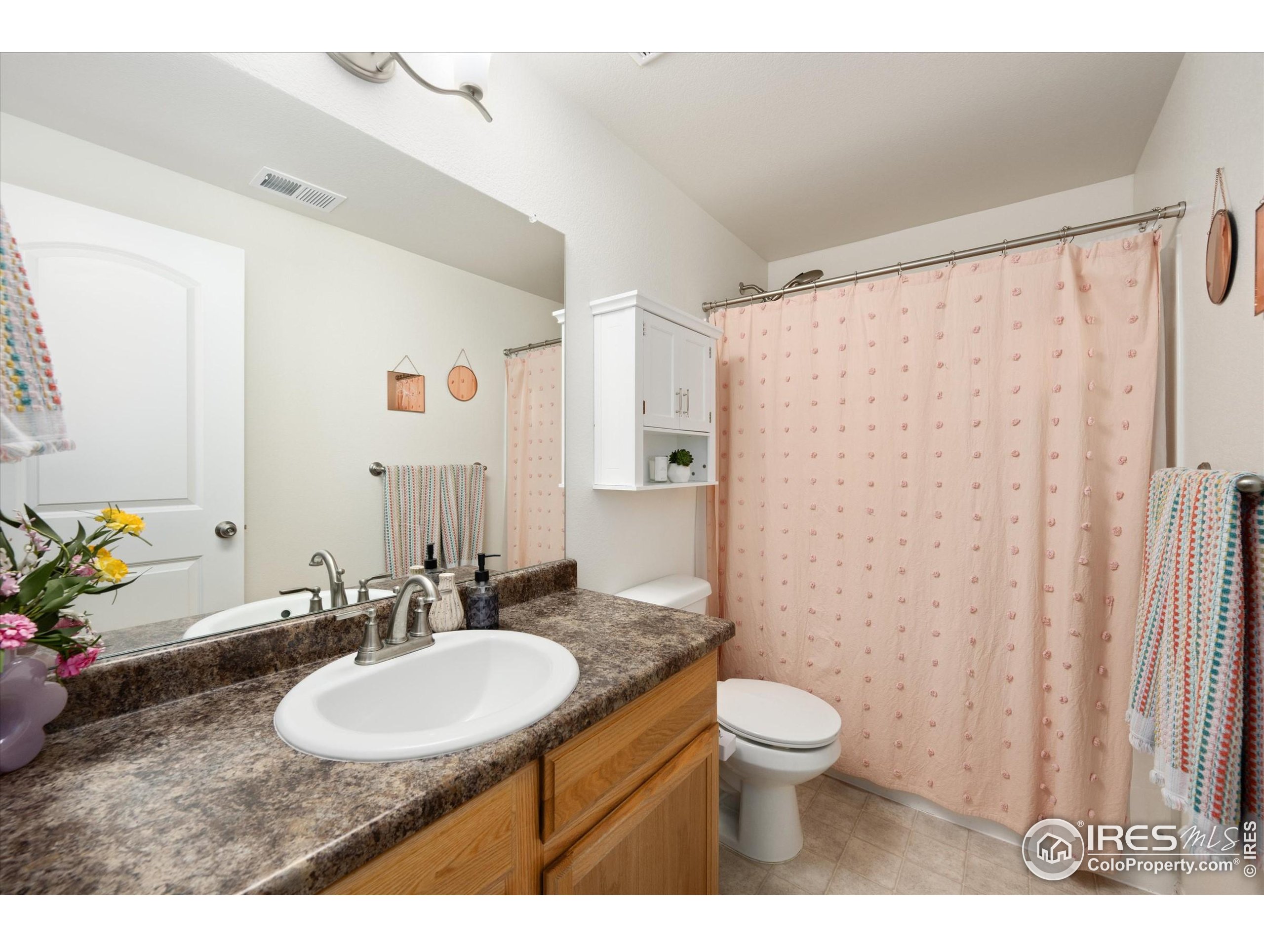 1995 Thundercloud Drive Windsor, CO 80550 - Photo 22 of 36 a bathroom with a granite countertop sink toilet a large mirror and shower curtain