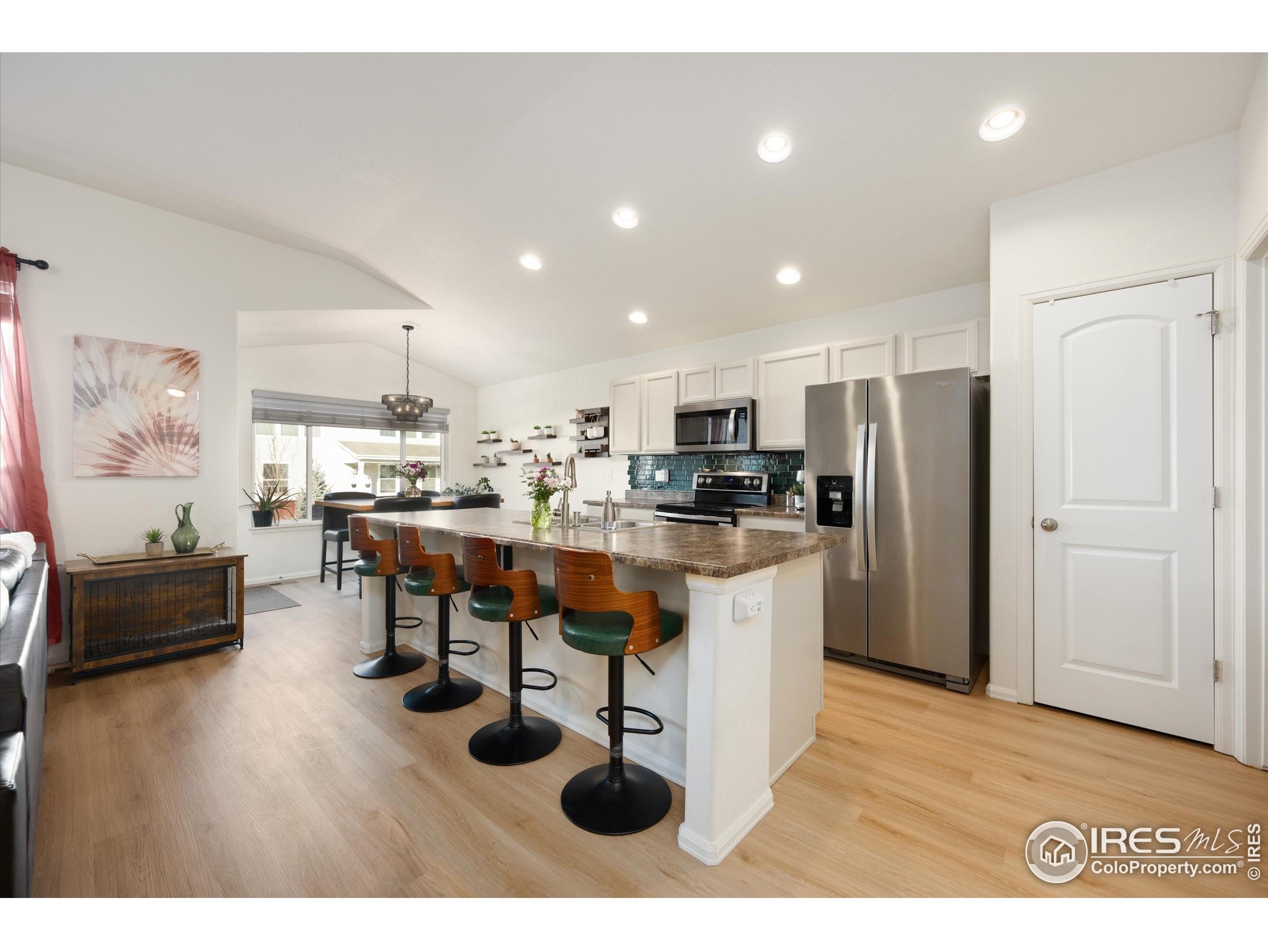 1995 Thundercloud Drive Windsor, CO 80550 - Photo 7 of 36 a kitchen with stainless steel appliances kitchen island granite countertop a refrigerator a stove a sink dishwasher and white cabinets with wooden floor