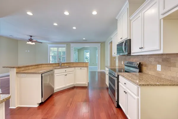 a large kitchen with granite countertop a large center island a sink stainless steel appliances and cabinets