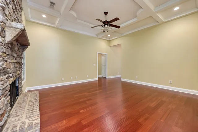 a view of an empty room with wooden floor and a ceiling fan
