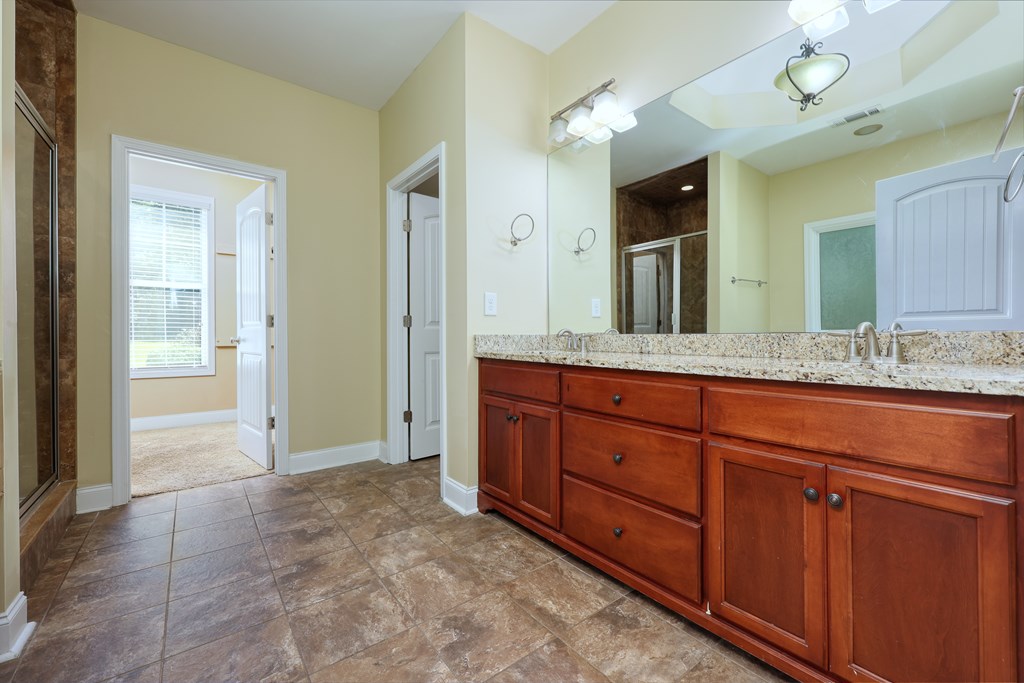 182 Oak Ridge Drive Waverly Hall, GA 31831 - Photo 30 of 40 a spacious bathroom with a granite countertop sink and a mirror