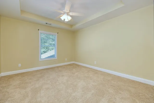 an empty room with windows and chandelier fan