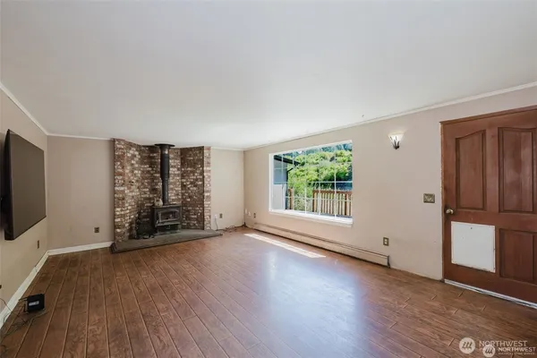 an empty room with wooden floor cabinet and windows