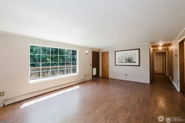 a view of an empty room with a window and wooden floor