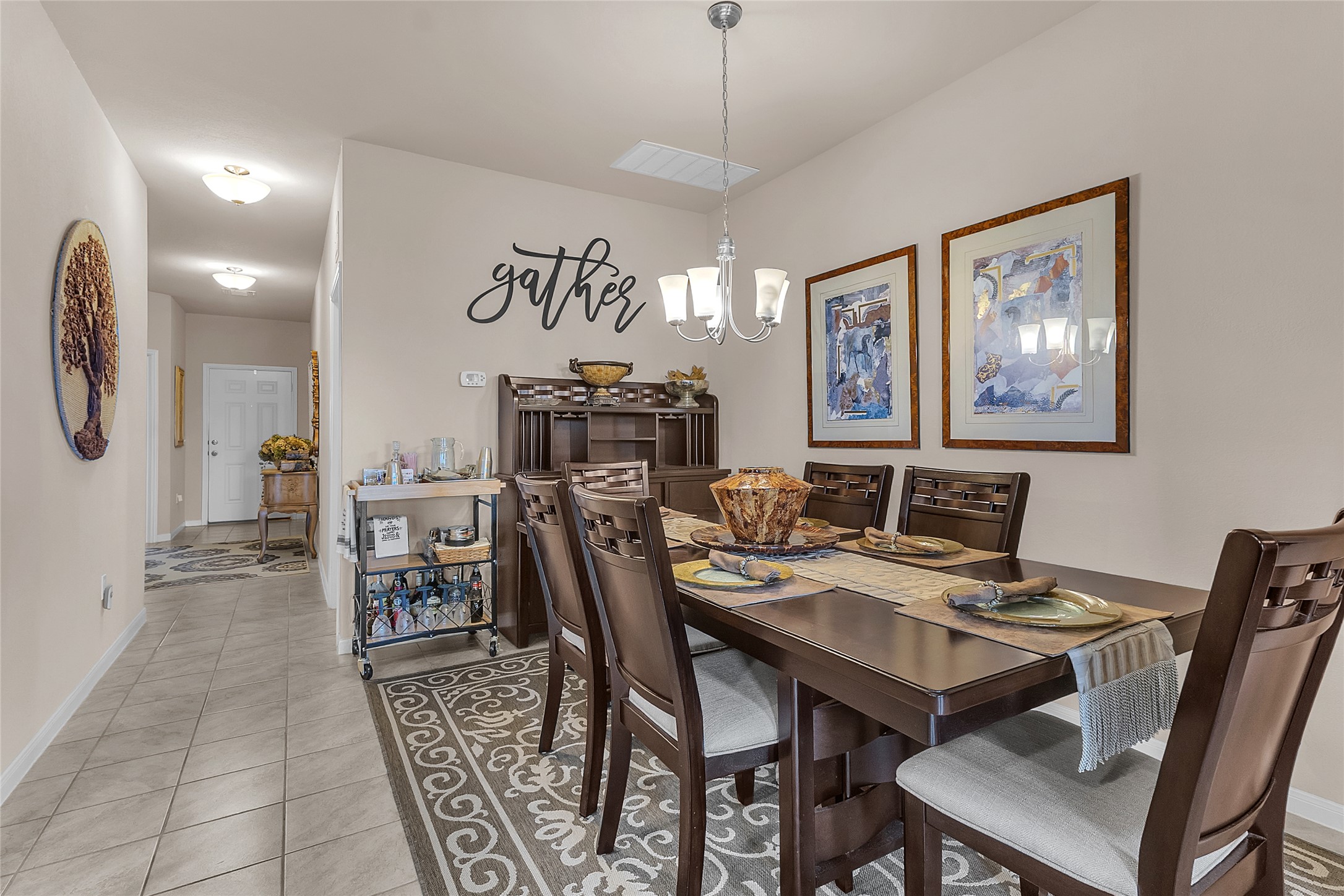 1608 Atlas Road Cedar Park, TX 78613 - Photo 8 of 17 An inviting dining room, adorned with a sophisticated chandelier and tile flooring, transitions seamlessly into a well-lit hallway.