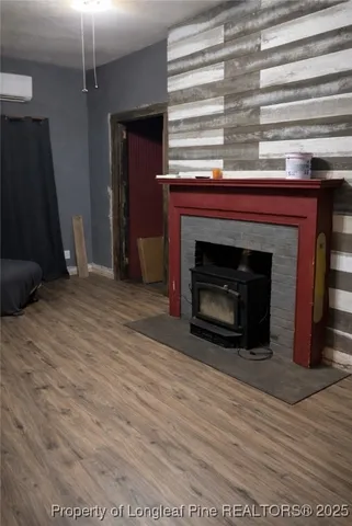 a view of an empty room with wooden floor fireplace and a window