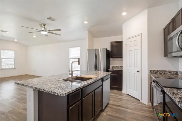 a kitchen with stainless steel appliances granite countertop a sink stove and refrigerator