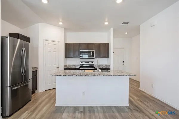 a kitchen with stainless steel appliances granite countertop a refrigerator a stove and a sink