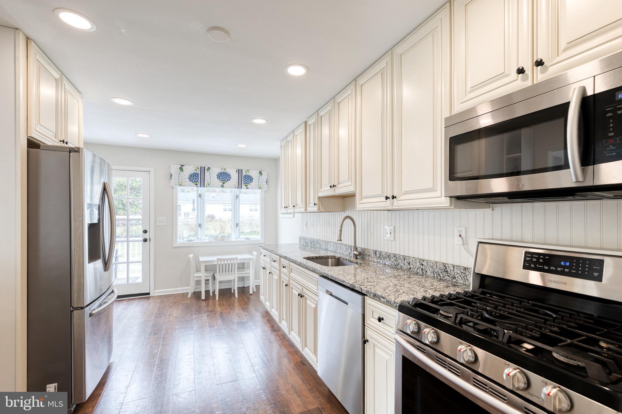 8206 Burnley Road Towson, MD 21204 - Photo 4 of 37 a kitchen with stainless steel appliances a stove a sink cabinets and a wooden floor