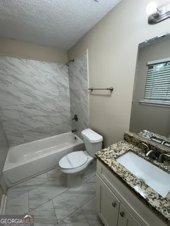 a bathroom with a granite countertop toilet a sink and bathtub