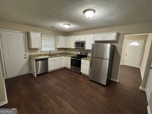a kitchen with stainless steel appliances granite countertop a refrigerator a stove a sink and a microwave