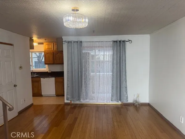 an empty room with wooden floor and a kitchen