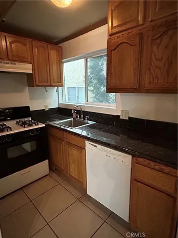 a kitchen with granite countertop a sink stove and cabinets
