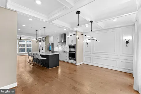 a kitchen with stainless steel appliances kitchen island granite countertop a refrigerator a oven a sink and a dining table with wooden floor