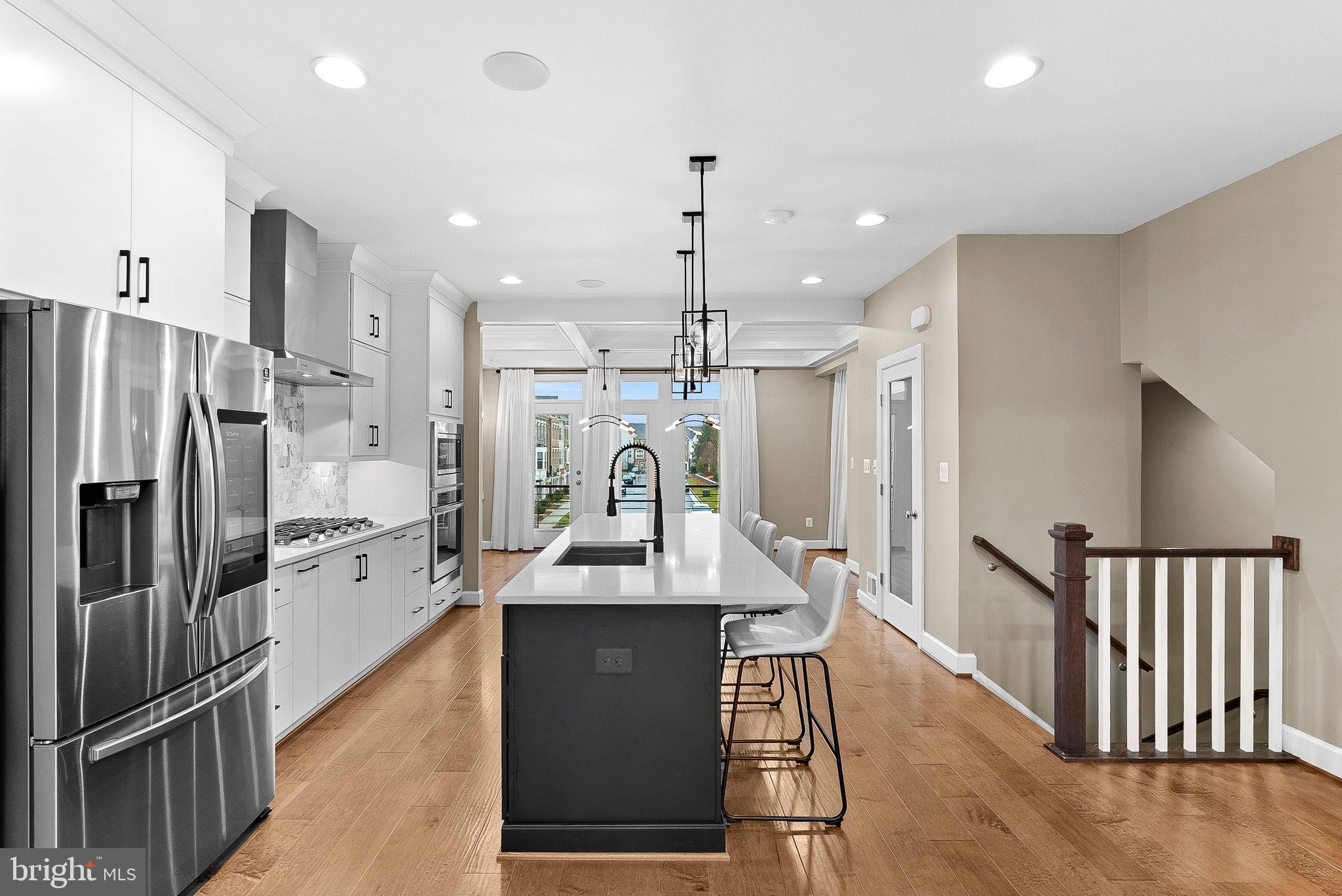 5159 Ridgeview Retreat Drive Chantilly, VA 20151 - Photo 16 of 59 a kitchen with stainless steel appliances kitchen island granite countertop a refrigerator a oven a sink and a dining table with wooden floor
