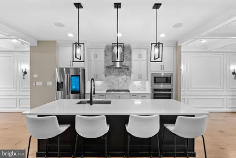 a kitchen with a stove a sink a kitchen island with chairs in front of it