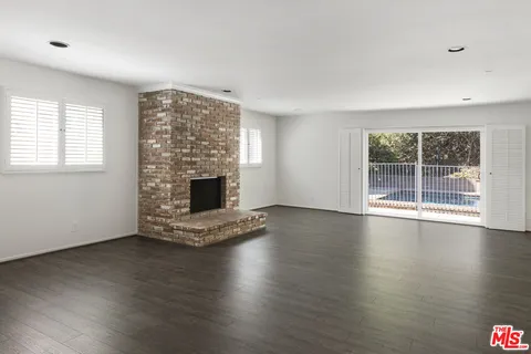 an empty room with wooden floor and fireplace
