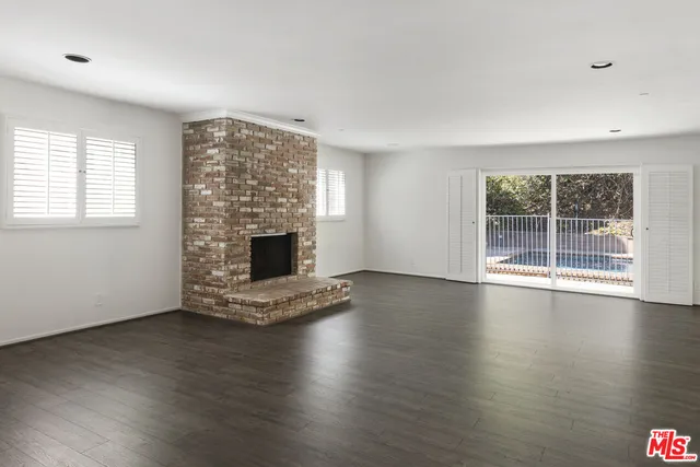 an empty room with wooden floor and fireplace