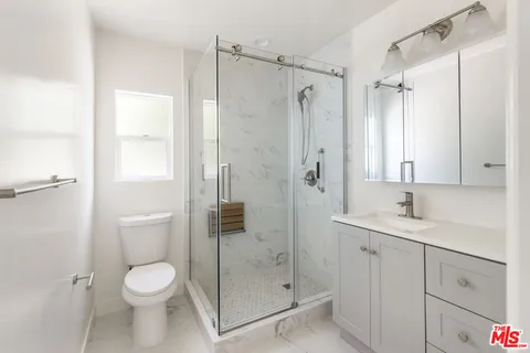 a bathroom with a shower sink vanity mirror and toilet