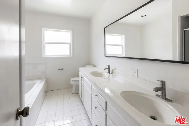 a bathroom with a double vanity sink a toilet and mirror