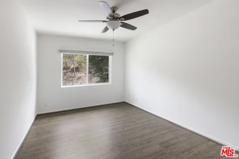 an empty room with a window and a ceiling fan