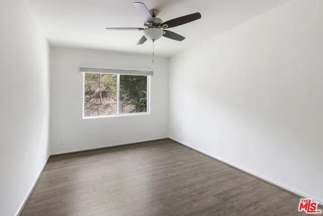 an empty room with a window and a ceiling fan