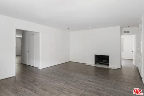 an empty room with wooden floor and a fireplace