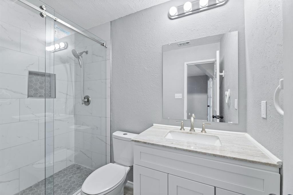 100 West Way Drive Allen, TX 75002 - Photo 14 of 31 Primary Full bath featuring a textured wall, a marble finish shower, vanity, and a textured ceiling