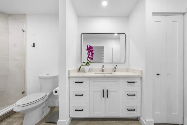 a bathroom with a toilet sink vanity and mirror