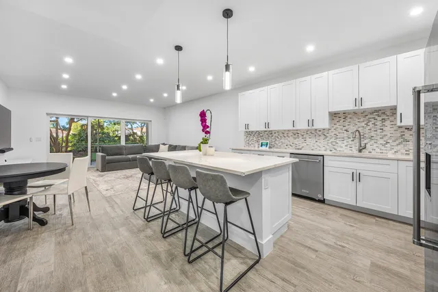a kitchen with stainless steel appliances kitchen island granite countertop a table chairs sink and cabinets