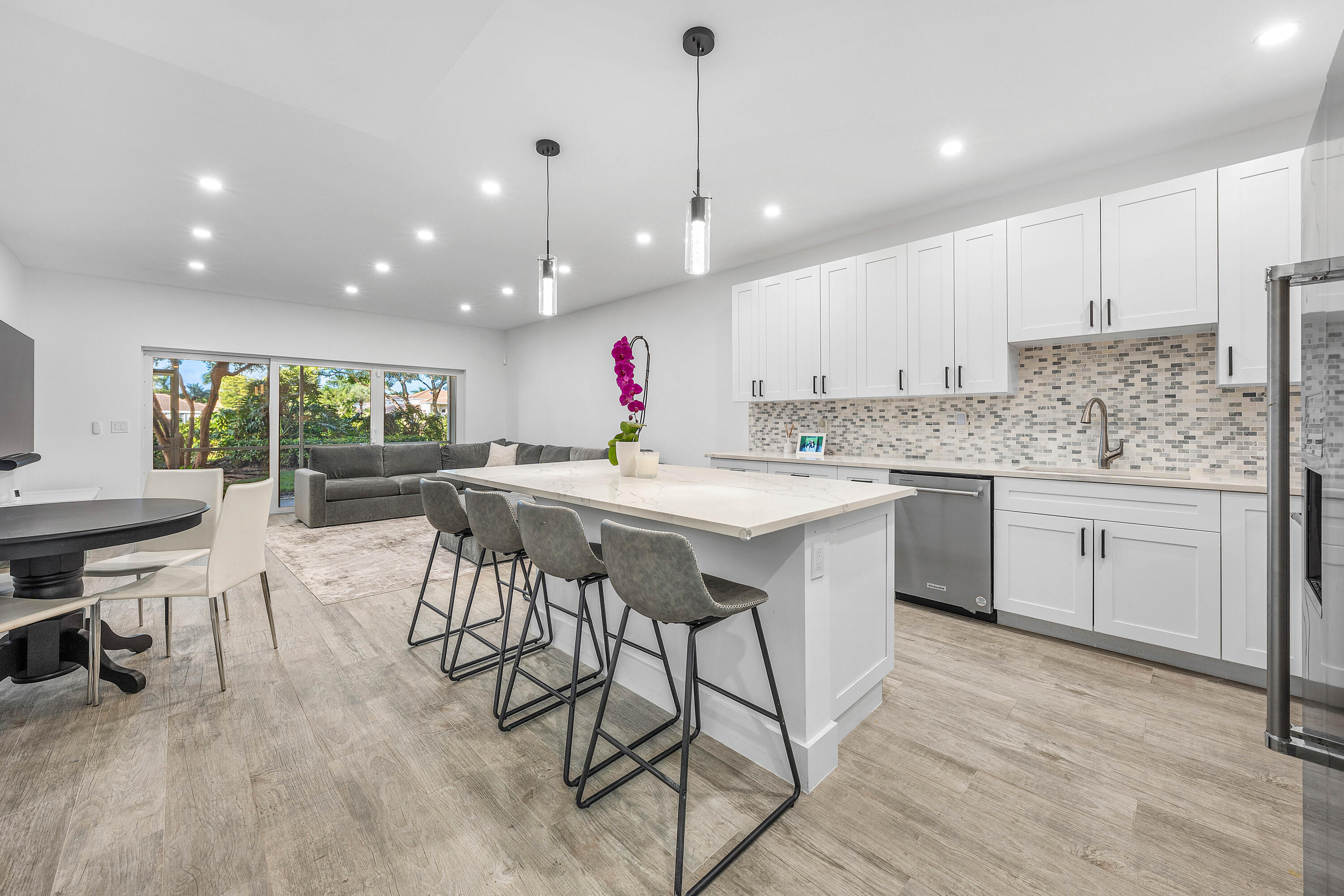 6229 Graycliff Drive, Unit A Boca Raton, FL 33496 - Photo 3 of 33 a kitchen with stainless steel appliances kitchen island granite countertop a table chairs sink and cabinets