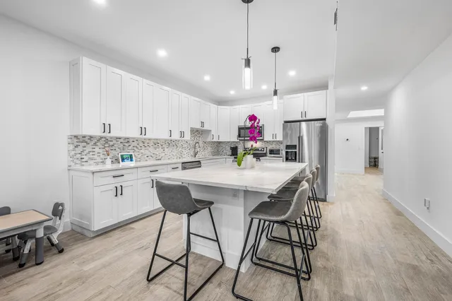 a kitchen with stainless steel appliances kitchen island granite countertop a wooden floor and white cabinets