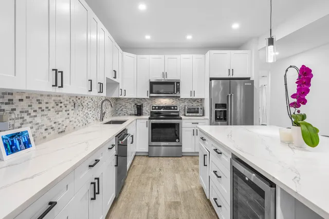 a kitchen with granite countertop a sink stainless steel appliances and white cabinets