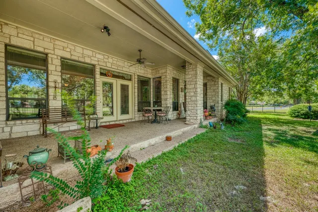 a view of a patio with table and chairs potted plants and large tree