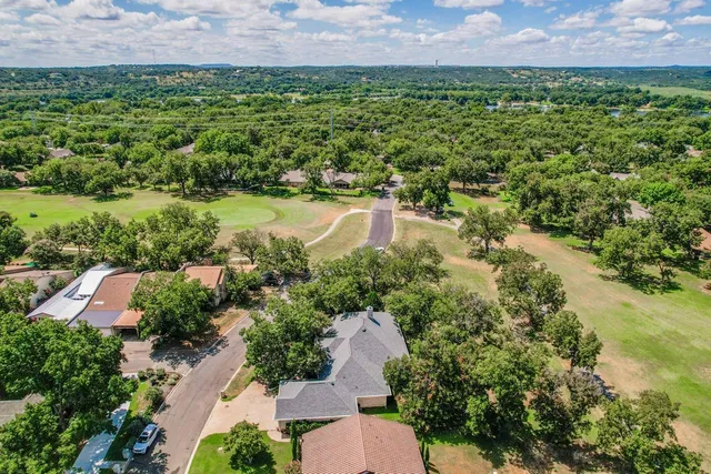 an aerial view of residential houses with outdoor space and trees all around
