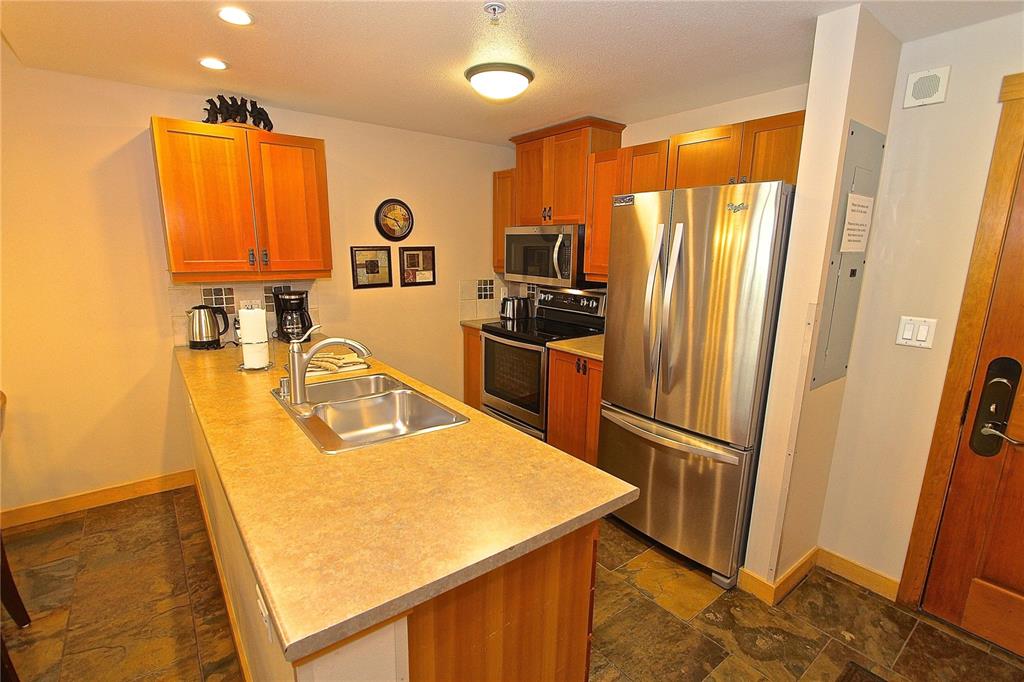 910 Copper Road, Unit 623 Copper Mountain, CO 80443 - Photo 3 of 24 a kitchen with stainless steel appliances granite countertop a refrigerator a stove and a sink with wooden floor