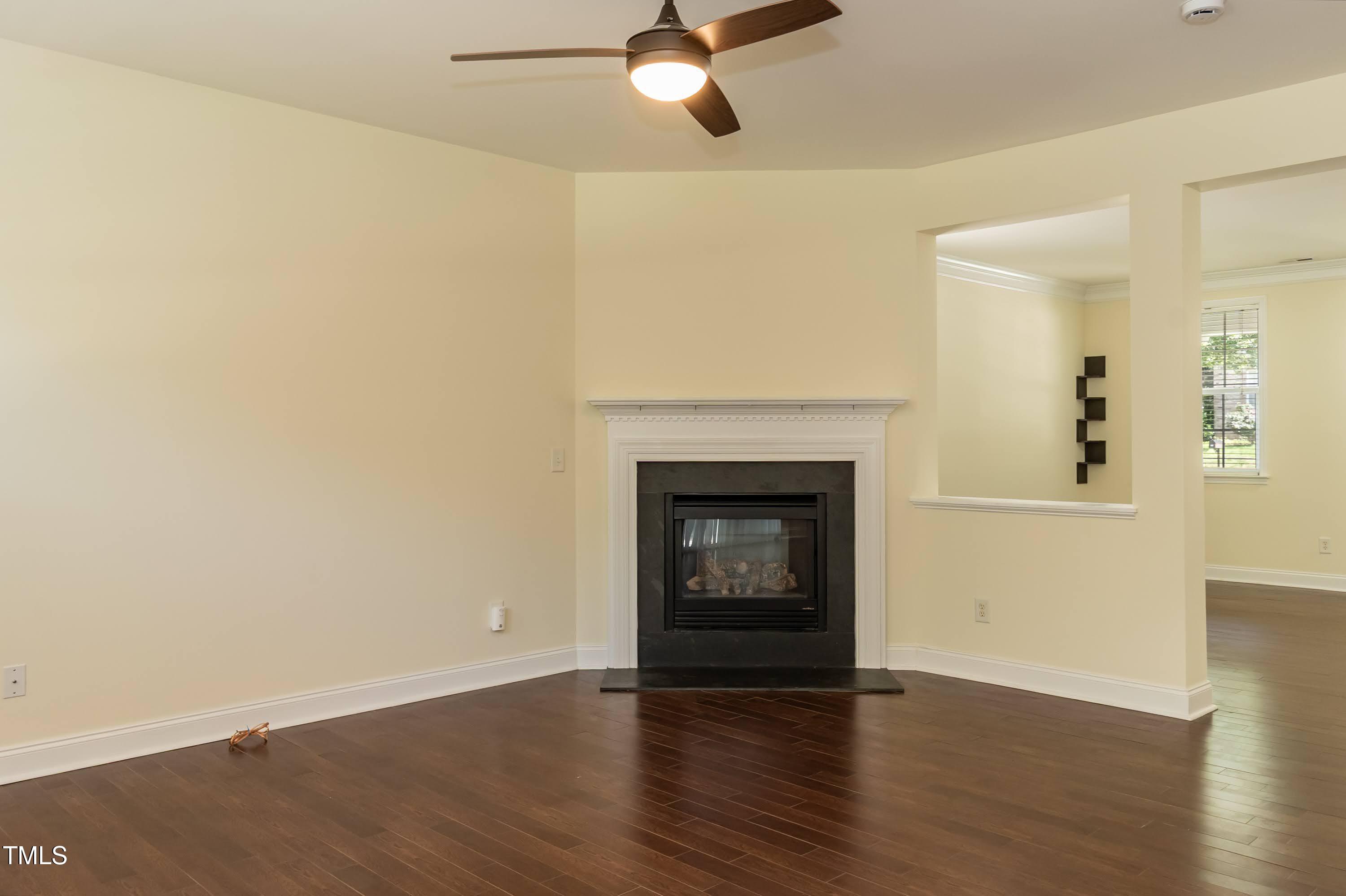 418 Byrams Ford Drive Cary, NC 27513 - Photo 11 of 53 an empty room with wooden floor a fireplace and a window