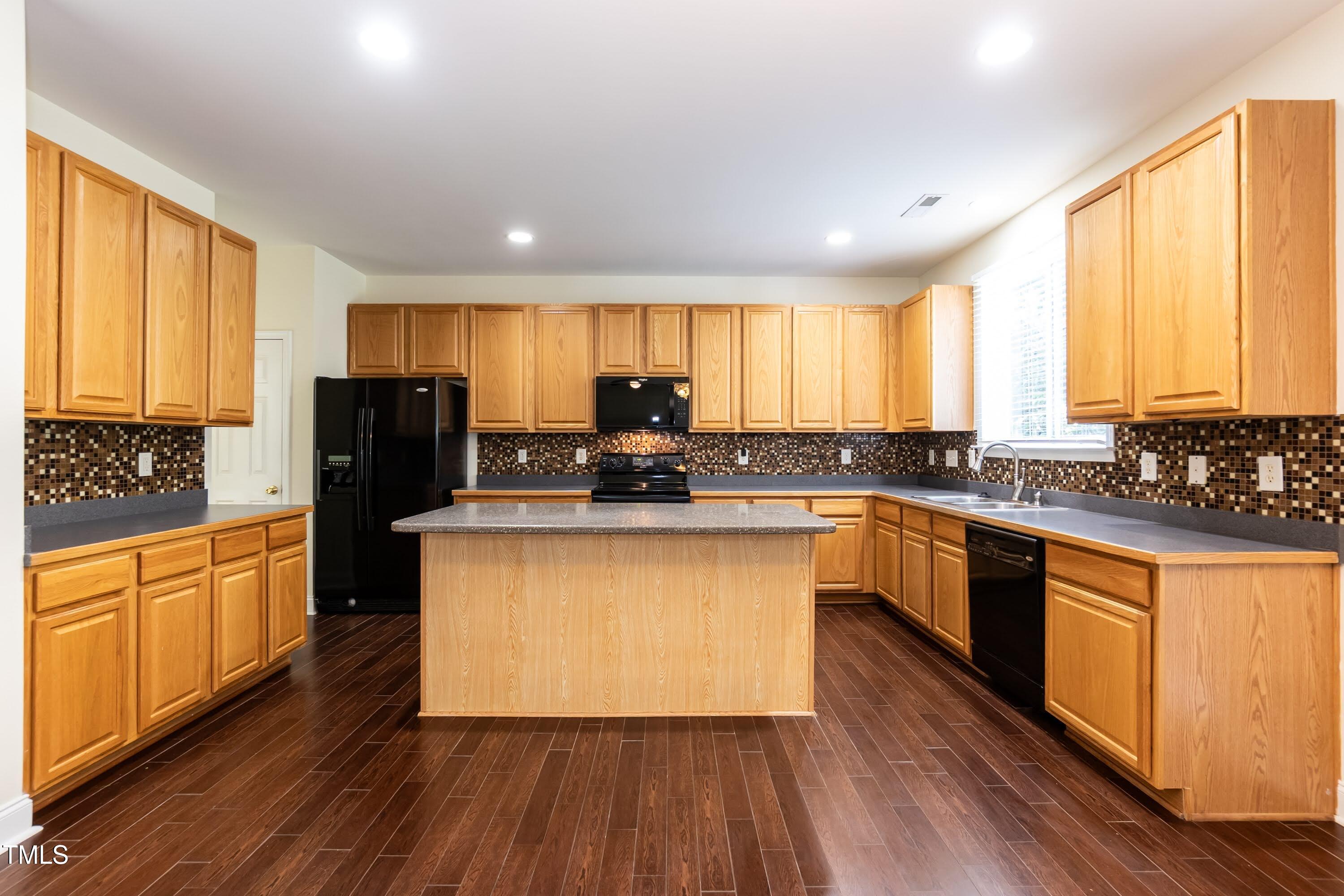 418 Byrams Ford Drive Cary, NC 27513 - Photo 16 of 53 a kitchen with granite countertop wooden floors stainless steel appliances a sink and a window